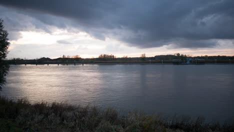 Zeitraffer-Wolkenlandschaft-Bei-Sonnenuntergang-Mit-Silhouettierter-Flussuferlinie