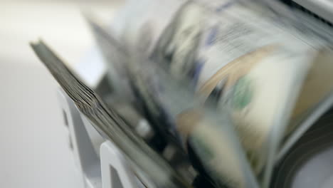 us hundred dollar banknotes turned quickly in the cash machine slot. equipment for currency calculation in banks. close up.