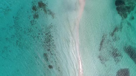 Stunning-aerial-top-view-sandbank-with-couple-isolated-on-paradise,-umbrella-and-boat