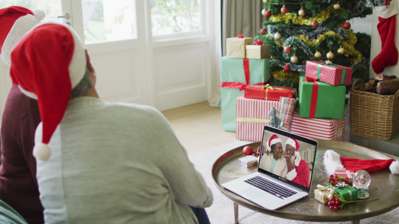 diversas amigas mayores que usan una computadora portátil para una videollamada de navidad con una pareja feliz en la pantalla