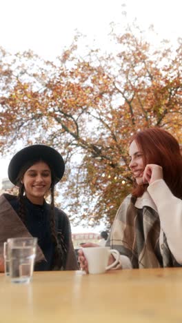 two friends enjoying coffee outdoors in autumn