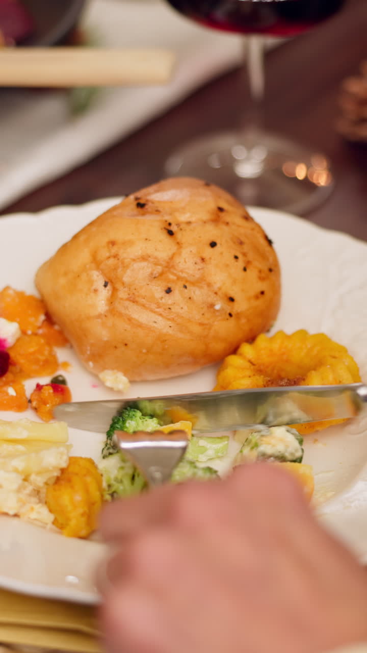 Primo piano di una mano che taglia pollo arrosto e verdure su un piatto