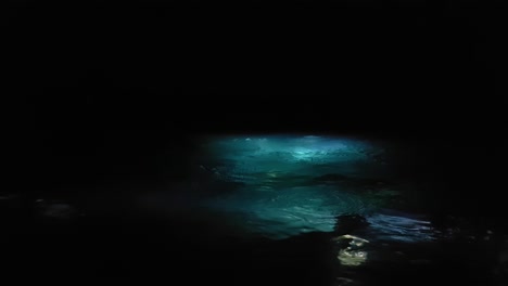 a large group of scuba divers using underwater torches to enter the ocean at night