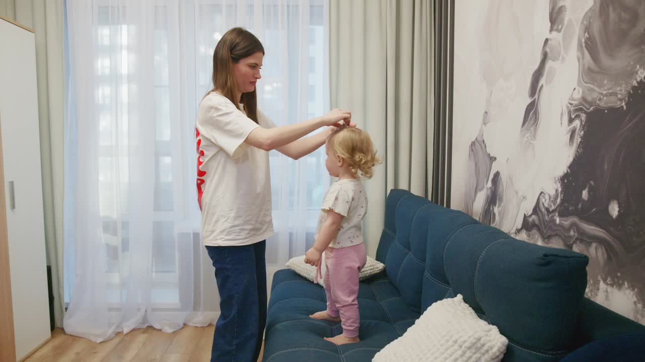 Young Mother Measuring Her Toddler Daughter's Height at Home