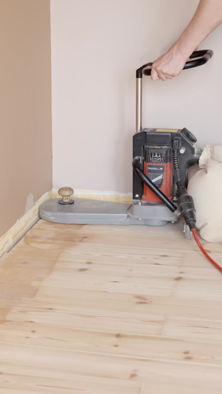 Sanding the edges of a wooden floor with a professional machine for a smooth finish