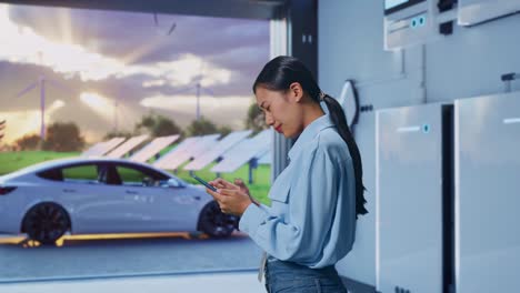 side view of asian female with her smartphone with home energy storage system in a modern garage, checking with dissapionted and nodding her shead