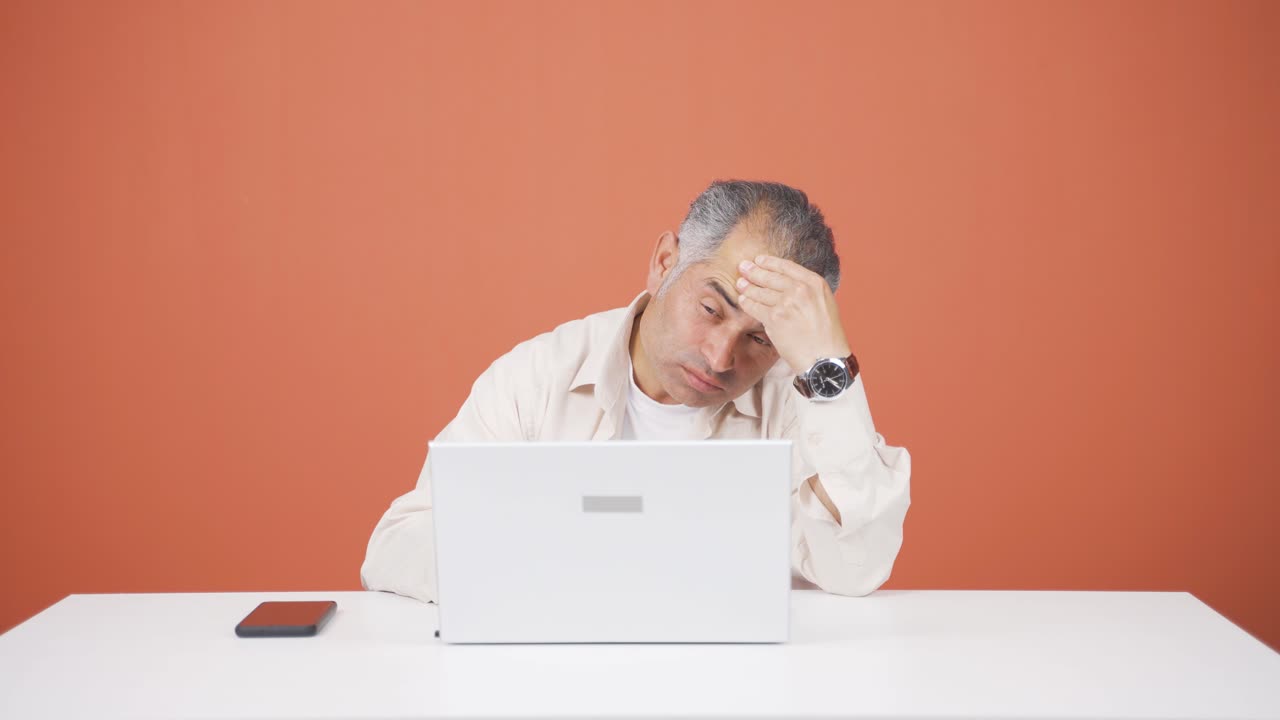 노트북으로 일하는 남자가 두통을  ⁇ 고 있습니다.