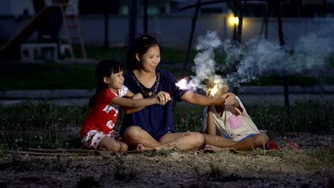 happy family, young mother with boy and girl fire holding sparkler at night.