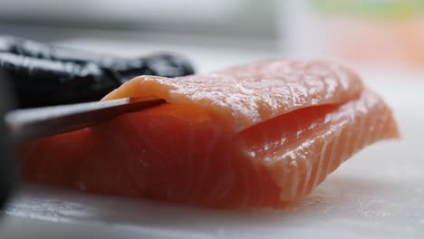 el cocinero corta el pescado rojo con un cuchillo.