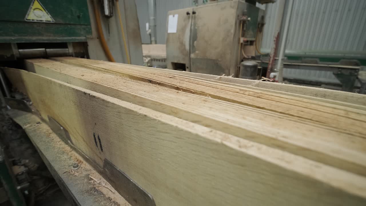 Tavole di legno che passano attraverso una macchina industriale da segheria
