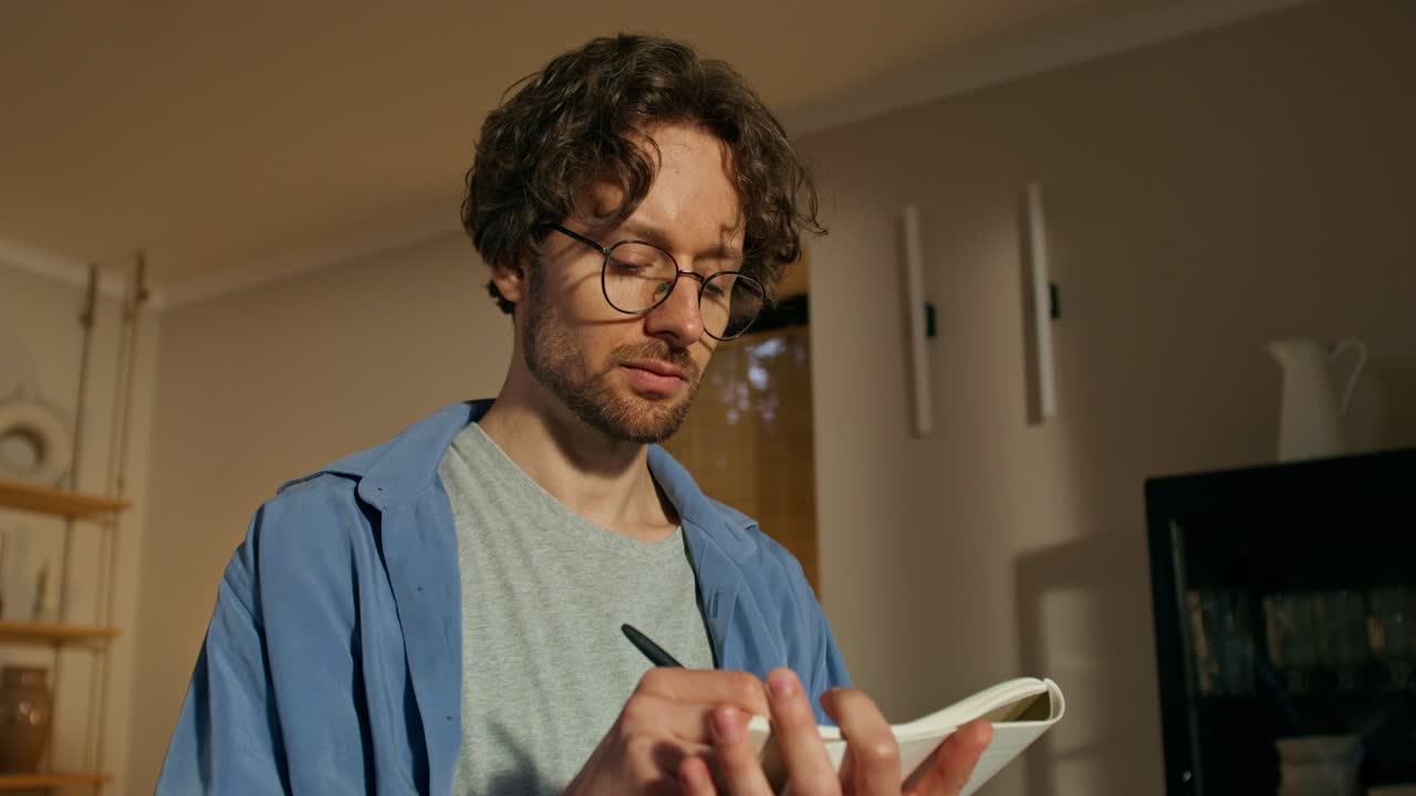 hombre escribiendo en un cuaderno en casa