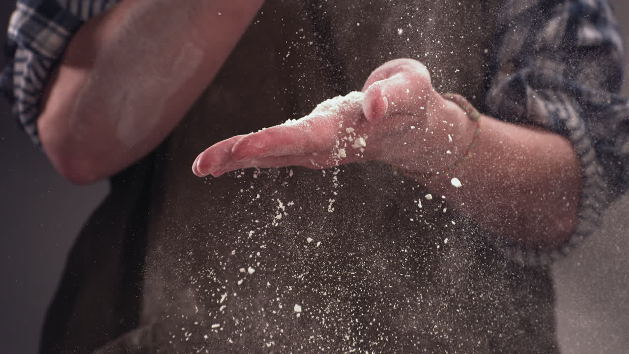 super cámara lenta mujer jefe de cocina aplaudiendo y salpicando harina sobre la masa en la mesa. filmado con cámara de alta velocidad a 720 fps