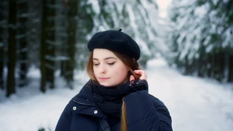 close up shot of young caucasian female fixing her hair while looking at the snow covered forest floor at daytime