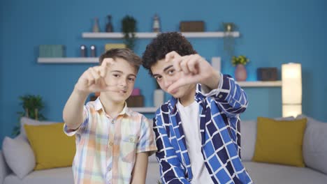 dos hermanos haciendo corazones para la cámara y riendo.