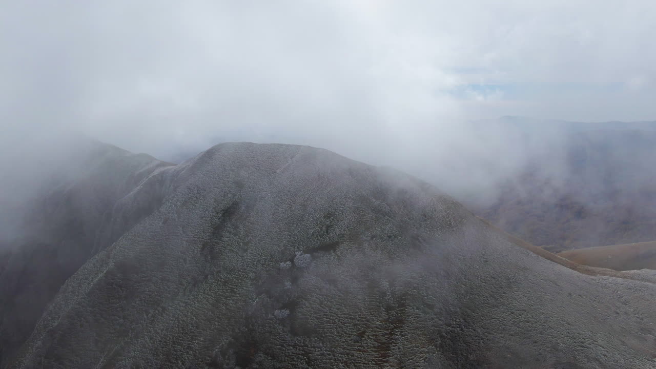 Under the early light of a chilly autumn morning, fog moves across the mountain’s crest, beautifully captured by a drone