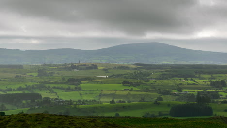 Lapso-De-Tiempo-Del-Paisaje-Rural-Con-Campos-De-Hierba-Y-Colinas-Durante-Un-Día-Nublado-En-Irlanda