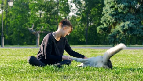 beautiful young woman playing with funny husky dog outdoors in park