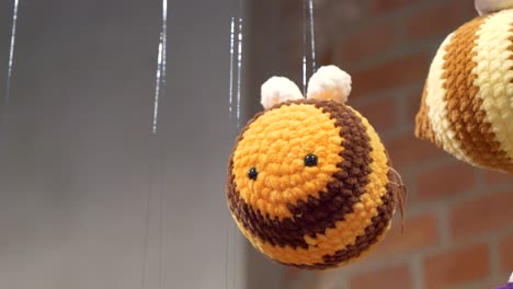 a yellow bee, a yarn mascot, hanging on a string