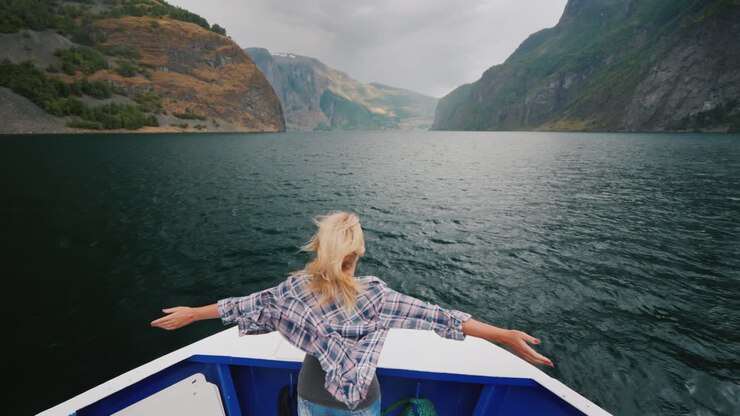Une femme se tient à la proue du navire, naviguant sur le fjord en Norvège et appréciant le voyage.