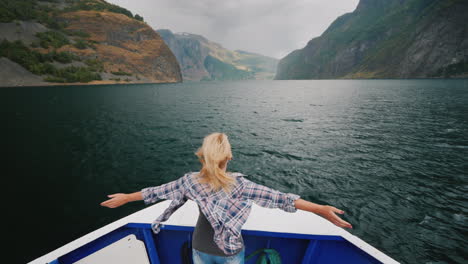 a woman is standing on the bow of the ship sailing over the fjord in norway enjoys the journey the w