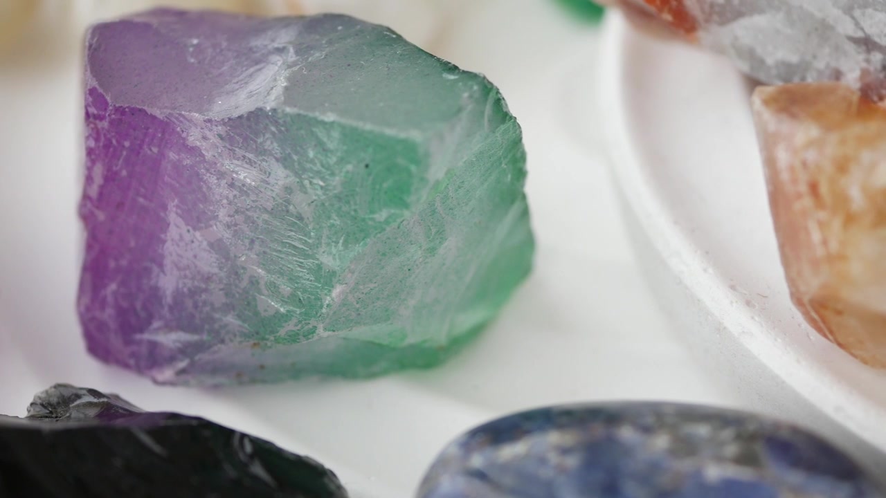 Primer plano de varias piedras preciosas y cristales en bruto sobre una superficie blanca
