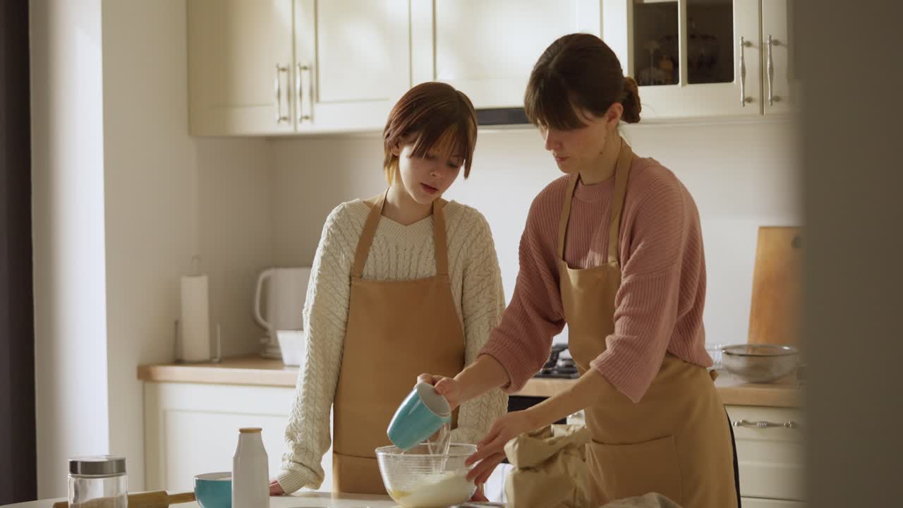 母 と 娘 が キッチン で 焼き物 を 作っ て いる