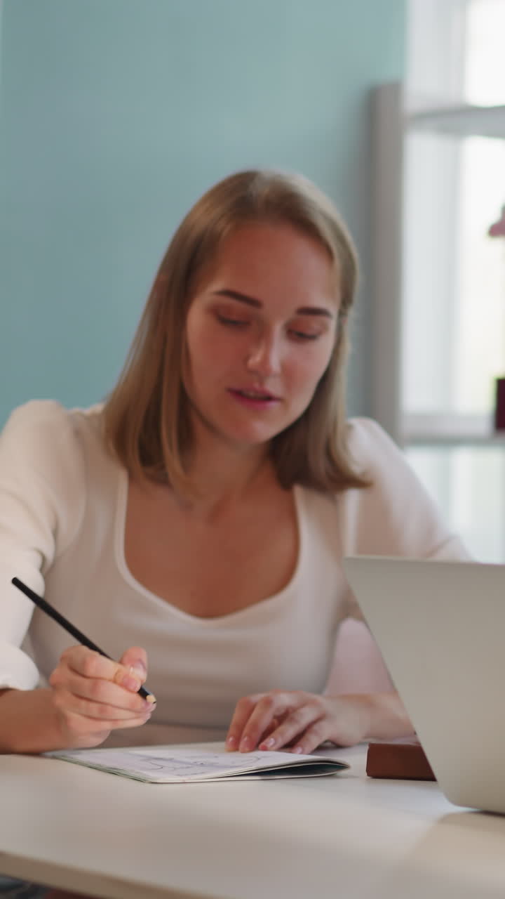 mujeres jóvenes se preparan para el examen final en la universidad juntas. estudiantes rubias y morenas se sientan en la mesa tomando notas y usando portátil