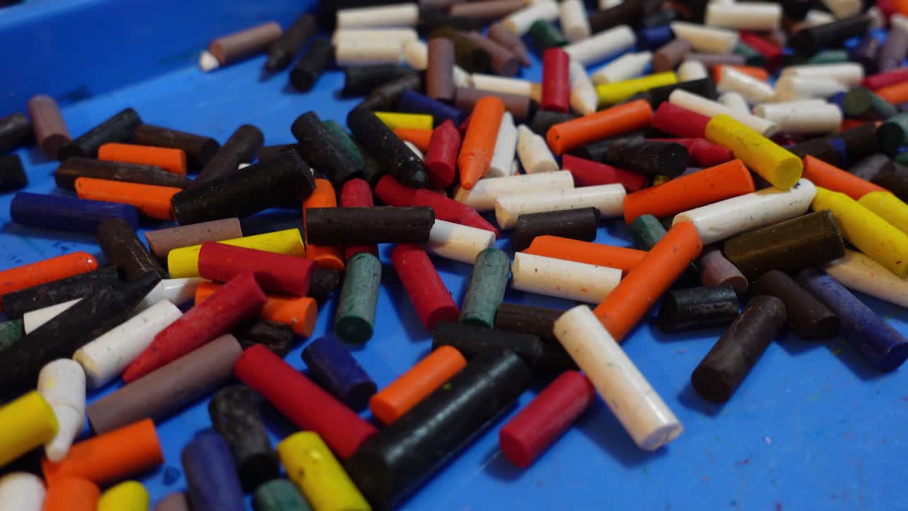 Colorful pile of broken crayons without paper on a blue surface