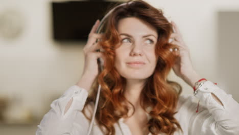 young woman putting headphones at modern kitchen. closeup girl enjoying music