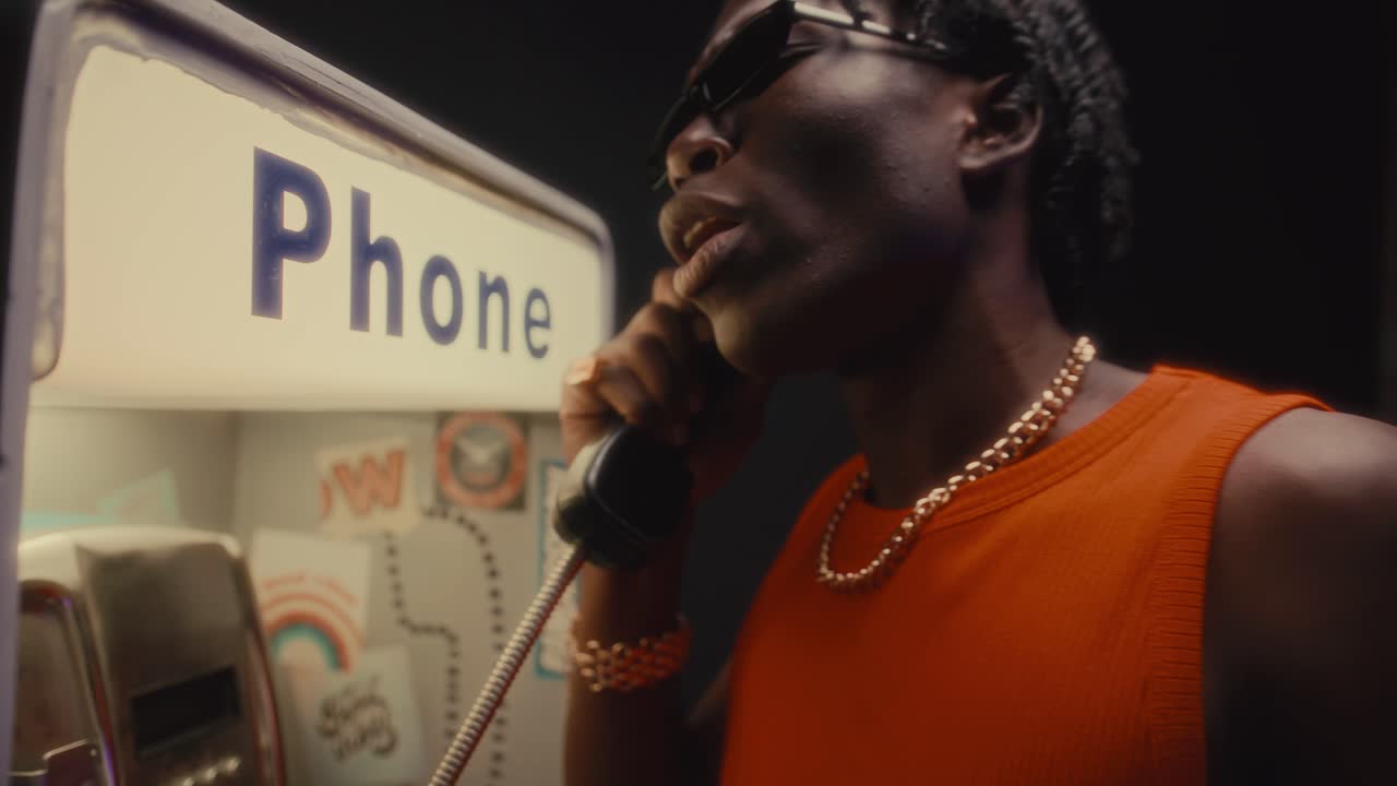 Fierce Black Man Having Intense Conversation on Payphone at Crime Scene