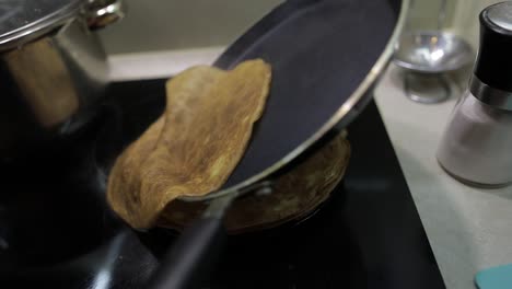 the process of cooking homemade pancakes. woman puts pancake from pan to plate