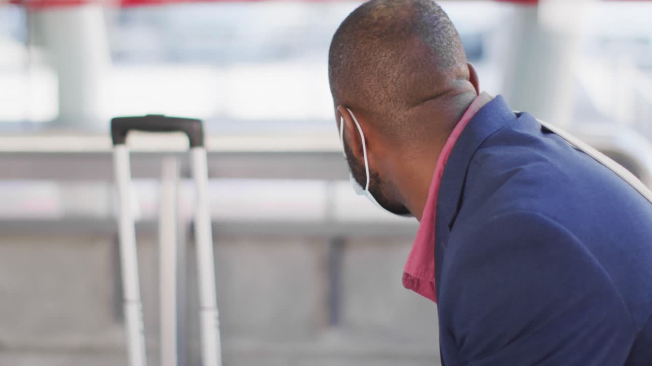 African american man in city wearing face, waiting for bus