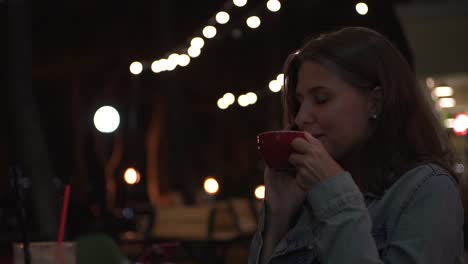 woman drinking coffee and talking on the phone at night