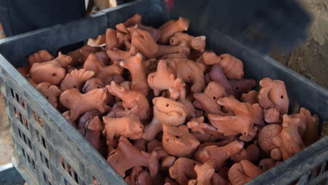 Close-up-view-of-hand-placing-traditional-clay-figurines-in-crate-southeast-asian-pottery-style-Than-Ha-Hoi-An,-Vietnam