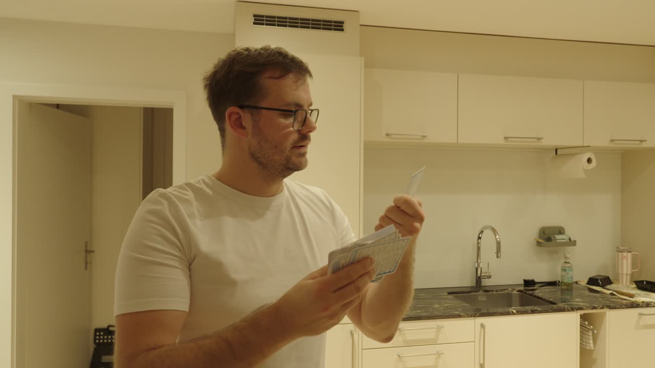A man studies with flashcards in the kitchen — learning, repeating, and memorizing information for exams or self-improvement