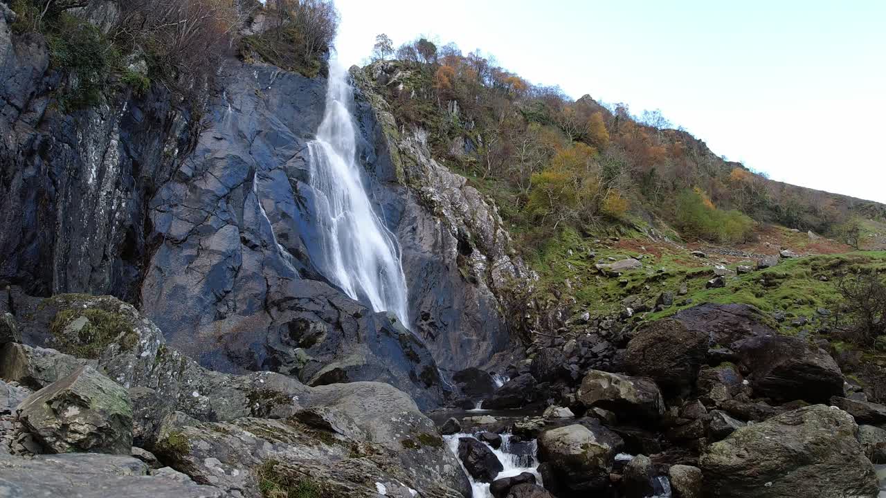 Cascata rocciosa in cascata che scorre in rocce e massi di fiume frastagliati a basso angolo
