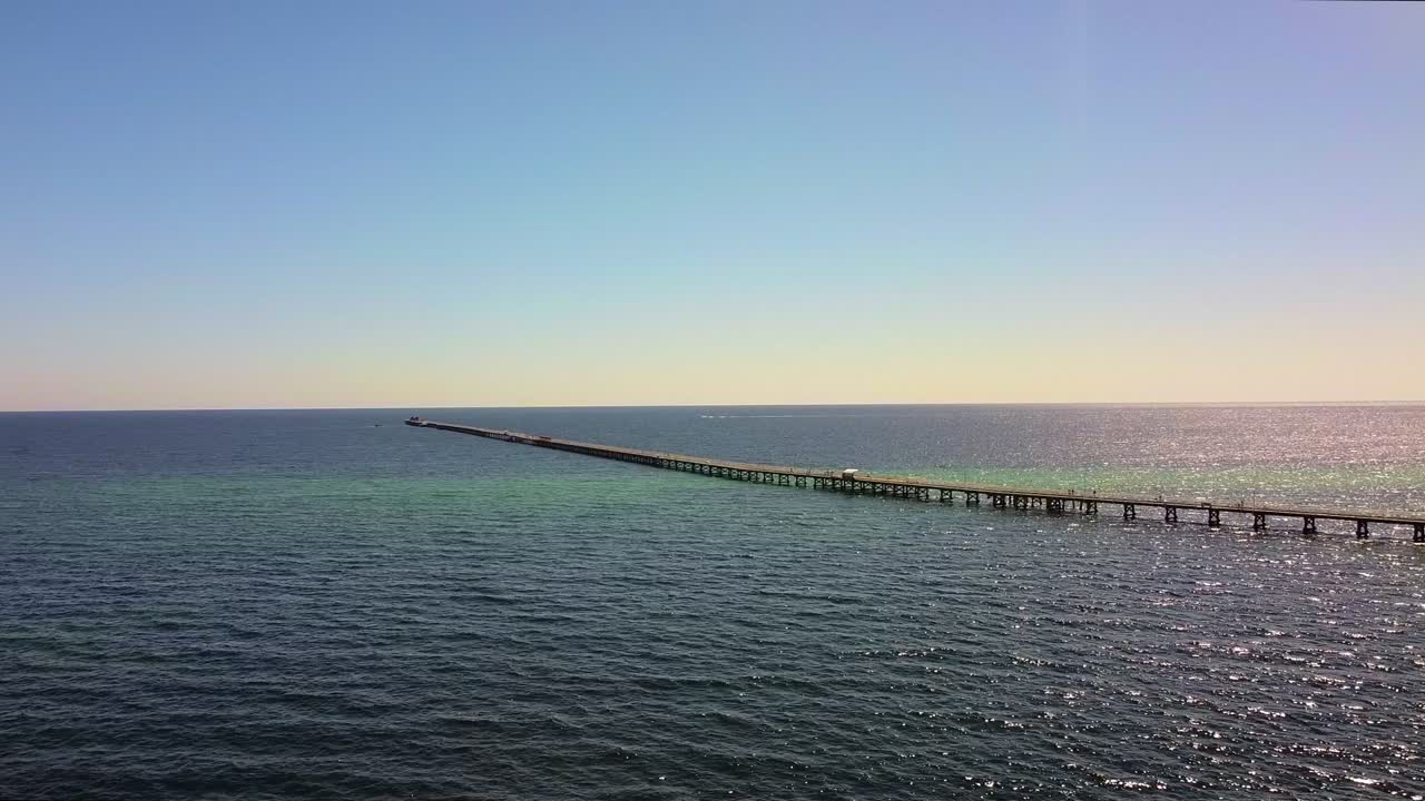 Long Pier Stretching into a Calm Ocean under a Clear Blue Sky