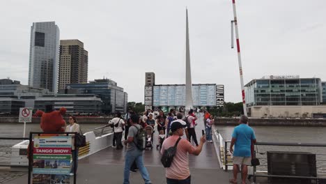 panning view of tourists visiting puerto madero, business center of buenos aires argentina at women's bridge landmark
