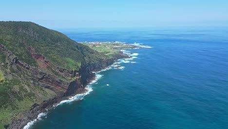 a rugged coastline with cliffs meeting the blue ocean under a clear sky, aerial view