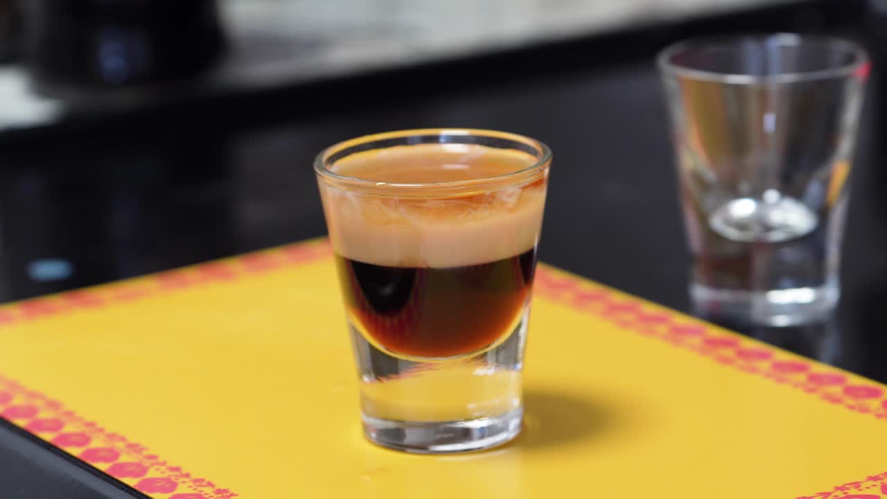 여성 손은 바 카운터에서 b52 칵테일 음료 한 잔을 가져갑니다.