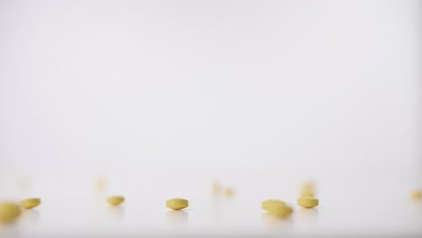 pastillas amarillas cayendo sobre fondo blanco en cámara lenta