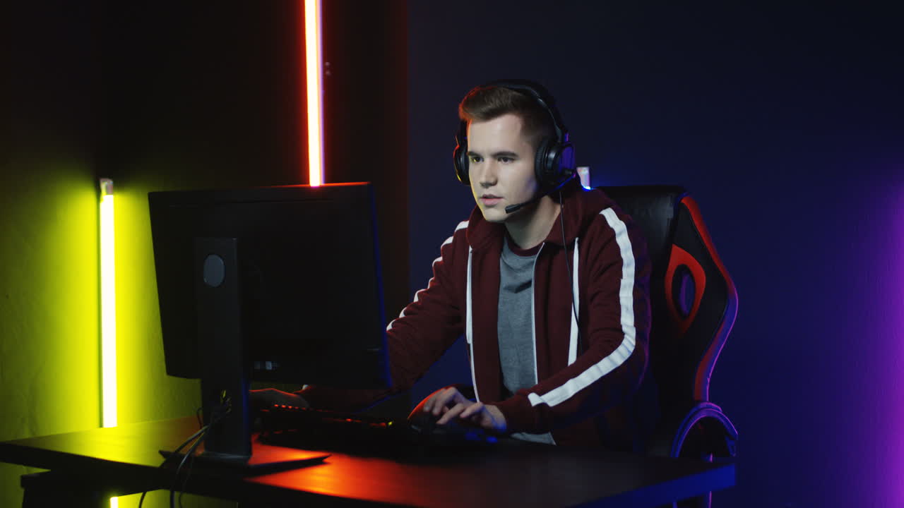 헤드폰을 끼고 컴퓨터에서 게임을 하고 1을 잃어 짜증이 난 젊은이의 시야를 닫습니다