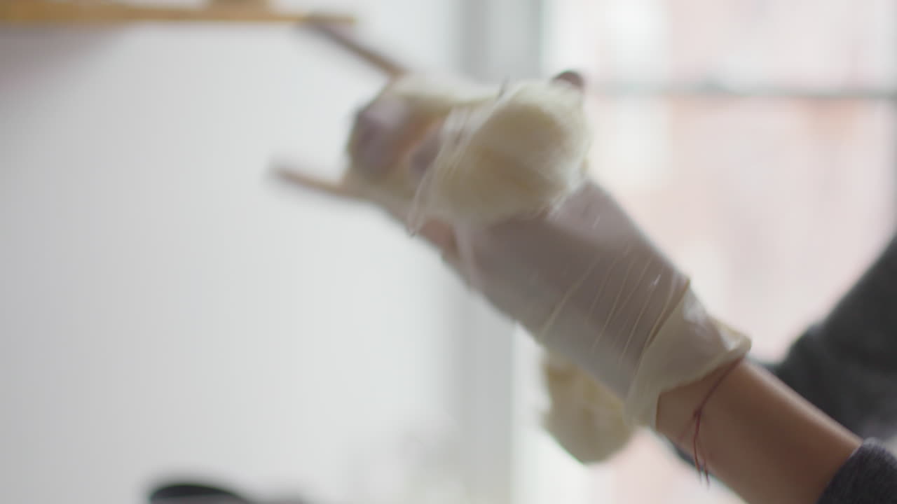 primer plano de las manos de la mujer mientras ata nudos de hilo