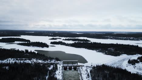 Wide-Landscape-Establishing-Aerial-Drone-Shot-Rushing-Water-Notigi-Hydro-Electric-Power-Lake-Dam-in-Snowy-Northern-Winter-Manitoba-Canada