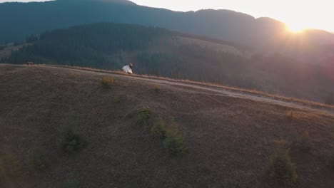 Newlyweds-dancing-on-a-high-slope-of-the-mountain.-Groom-and-bride.-Aerial-view