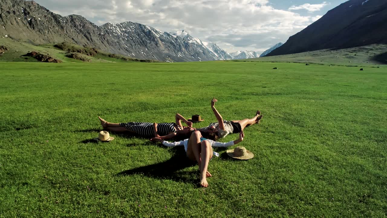 초록 잔디 위에 누워있는 세 명의 매력적인 소녀들이 잔디에서 즐거움을 즐기고 있습니다.