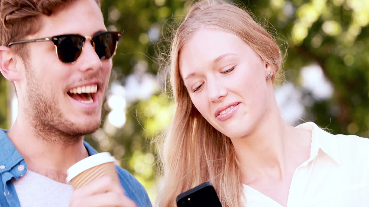 Coppia alla moda sorridente che usa lo smartphone
