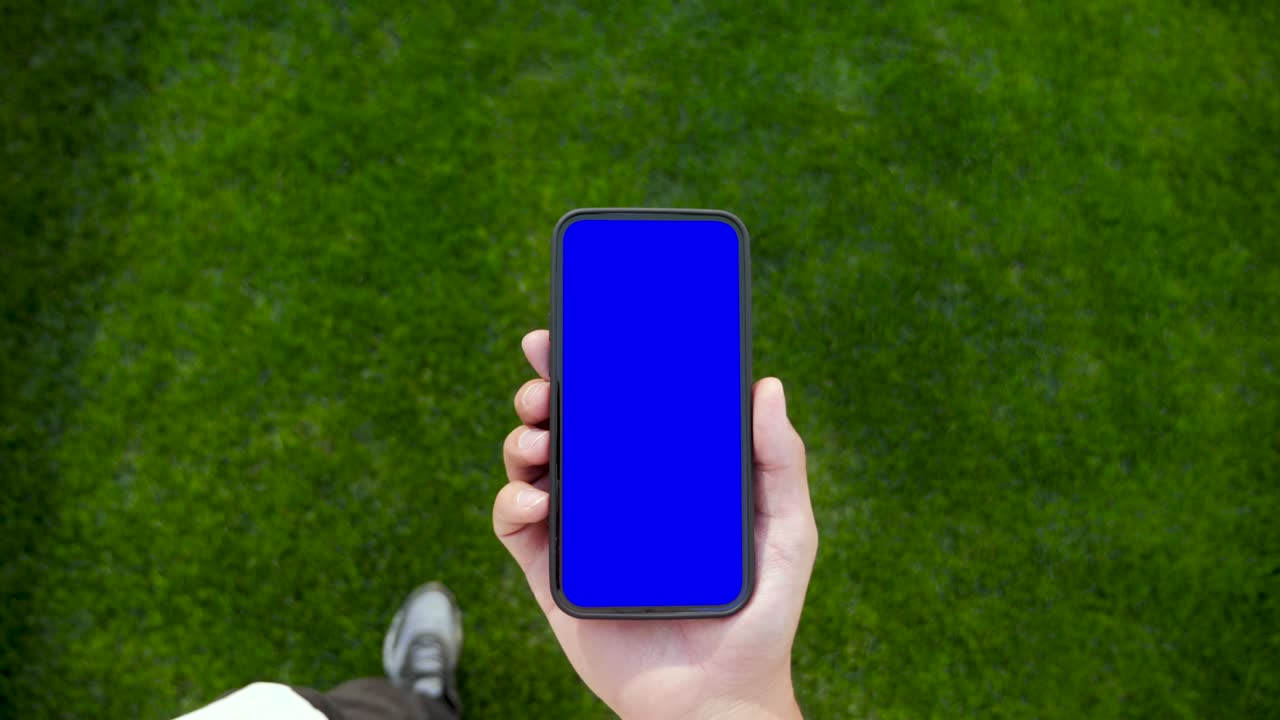 persona sosteniendo en la mano un teléfono inteligente con pantalla verde clave de croma y hablando de llamada de video. hombre caucásico adulto joven usa el teléfono para redes sociales o compras electrónicas. concepto de caminata con visualización de pantalla inteligente