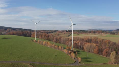 Windkraftanlagen-An-Einem-Sonnigen-Tag-In-Der-Nähe-Des-Dorfes,-Umgeben-Von-Einer-Wiese