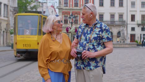 senior couple grandmother grandfather tourists talking on city street, holidays vacation traveling